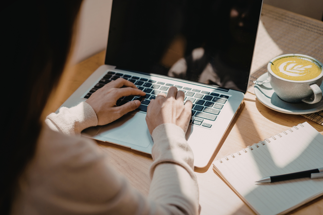 Business professional working at a modern desk with a coffee cup and laptop in a bright office
